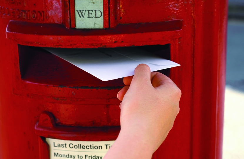 Person posting a letter through a red post box